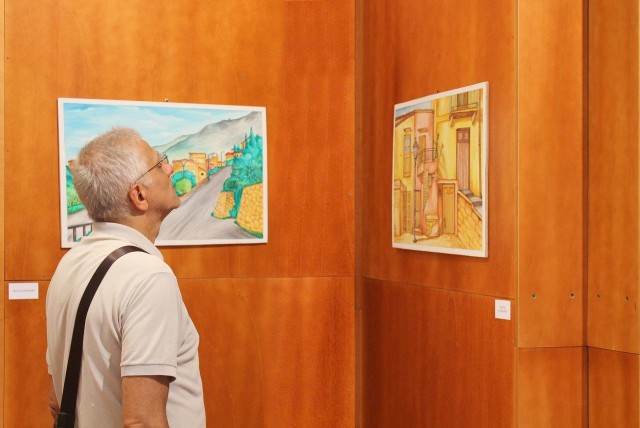 Un visitatore osserva il quadro "Piazzetta con ballatoio"